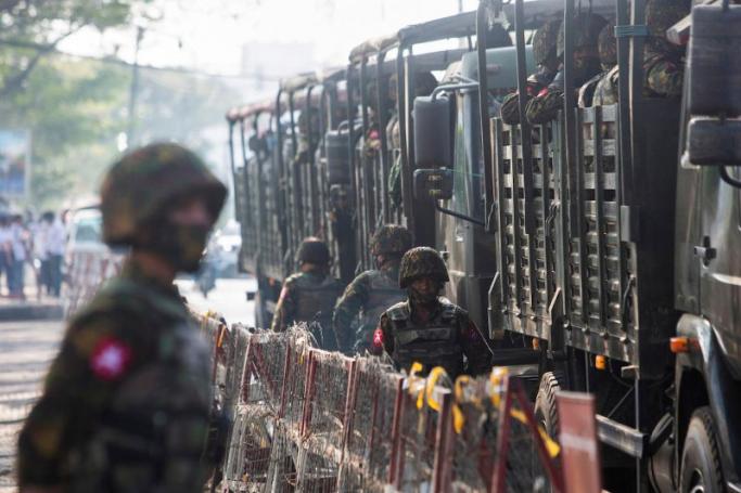 Soldiers stand next to military vehicles as people gather to protest against the military coup, in Yangon, Myanmar. Photo: REUTERS