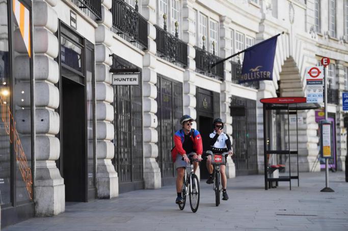 People cycle past closed shops on Regent Street in London, Britain, 14 April 2020. Photo: EPA