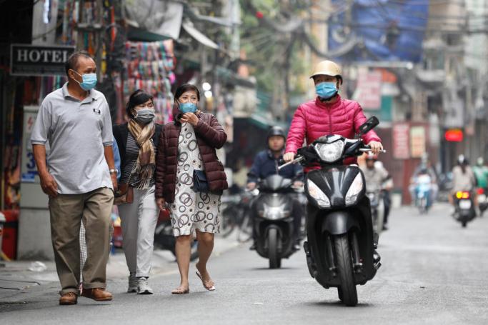People wearing face masks walk on a street in Hanoi, Vietnam. Photo: EPA