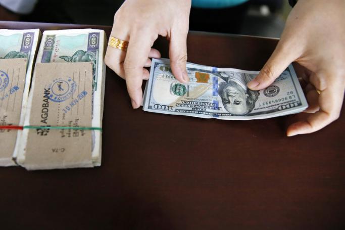Staff member of a money exchange center counts US dollar notes during an exchange, in Yangon, Myanmar. Photo: EPA