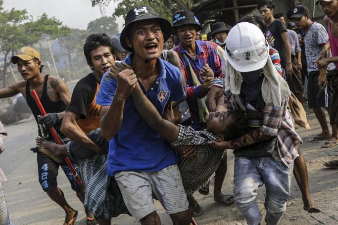 An injured demonstrator is carried to receive medical attention during a protest against the military coup in Hlaingthaya (Hlaing Tharyar) Township, outskirts of Yangon, Myanmar, 14 March 2021. Photo: EPA