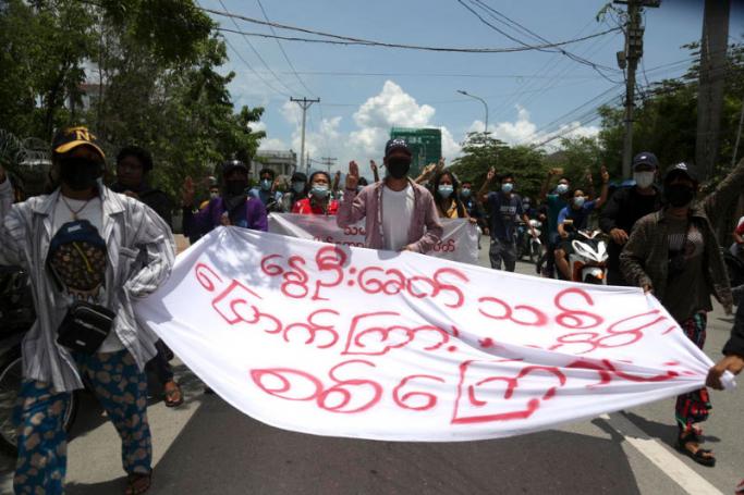 Myanmar demonstrators flash three-finger salute as they march on a street during an anti-military coup protest in Mandalay, Myanmar. Photo: EPA
