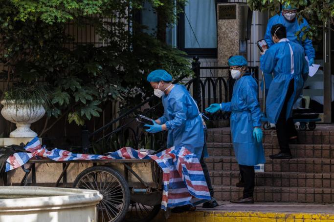 Community employees in protective gear deliver food rations in a residential community under lockdown in Shanghai, China. Photo: EPA