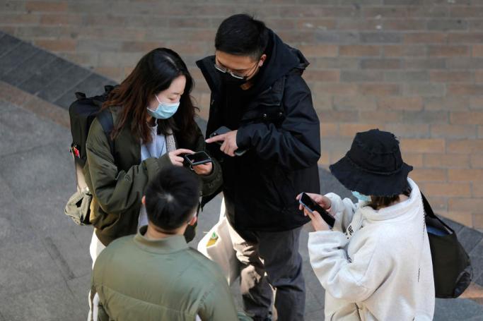 People wearing protective masks use mobile phones in Beijing, China, 11 March 2020. Photo: EPA