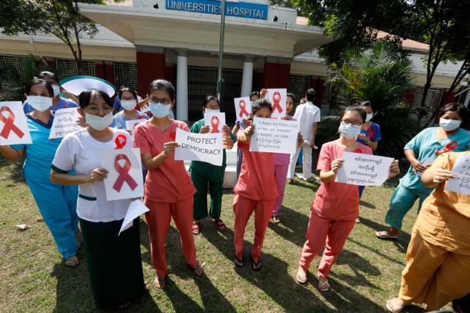 Doctors and nurses from Universities Hospital hold up signs of the red ribbon and placards as they participate in the civil disobedience campaign against the military coup in Yangon, Myanmar, 05 February 2021. Photo: EPA
