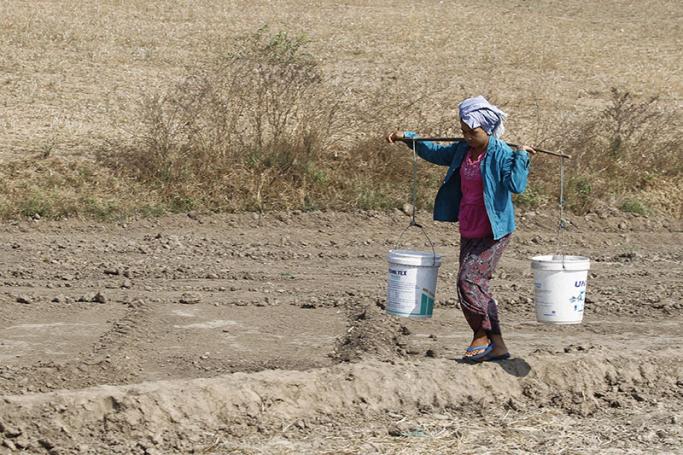 A Myanmar woman carries buckets to collect drinking water. Photo: Hein Htet/EPA
