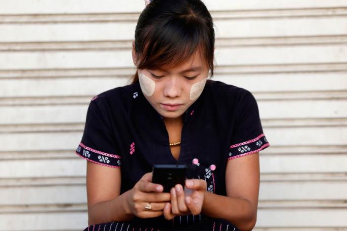 A woman using her smartphone in Pyinmana city near Nay Pyi Taw, Myanmar, November 10, 2014. Photo: Rungroj Yongrit/EPA
