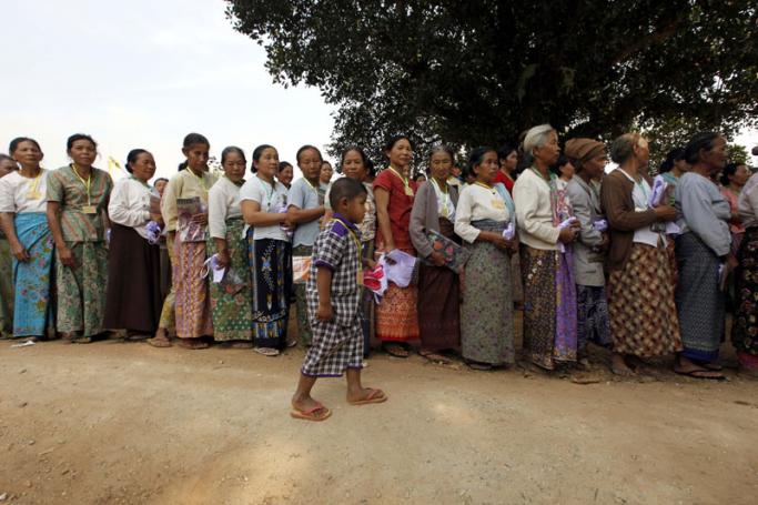 Elderly women queue to receive donations, as a child walks past, as they gather in a monastery which is being set up as a temporary refugee camp in KyaukMe, northern Shan State, Myanmar, 20 February 2016. Photo: Hein Htet/EPA
