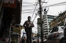 Myanmar man passes by electric pole with cables at a roadside at downtown area in Yangon, Myanmar. Photo: EPA