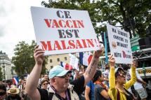 A protester holds poster reading 'this vaccine is unhealthy' during a demonstration held by right-wing party 'Les Patriotes' against the COVID-19 sanitary pass which grants vaccinated individuals greater ease of access to venues, in Paris, France, 21 August 2021. Photo: EPA