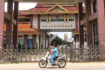  A woman rides a scooter with a child past the China-Myanmar border gate in Muse in Shan state on July 5, 2021, as the Chinese city of Ruili near the border with Myanmar imposed a lockdown and started mass testing after three Covid-19 coronavirus cases were reported on Monday.  Photo: AFP