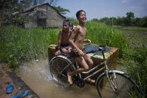 Children play while washing their bicycle at a water tank in Ma Sel Seik village in Kawhmu township, Yangon. Photo: Ye Aung Thu/AFP
