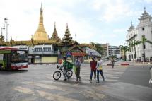 Pedestrians cross a road across the Sule Pagoda (L) in Yangon. Photo: AFP