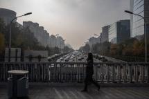 A woman walks on a bridge over a road carrying cars on a polluted day in Beijing, China. Photo: EPA