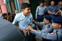 Detained Reuters journalist Kyaw Soe Oo (C) is escorted by police as he tries to talk with the media as he leaves after his trial at the court house in Yangon, Myanmar, 11 April 2018. Photo: Lynn Bo Bo/EPA-EFE
