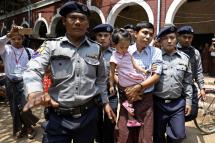 Detained Reuters journalist Kyaw Soe Oo (C) is escorted by police as he holds his daughter during a break in the trial at the court in Yangon, Myanmar, 28 March 2018. Photo: Nyein Chan Naing/EPA-EFE
