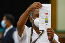 An election official holds up a ballot as they count votes at a polling station, after polls closed, in Naypyidaw on November 8, 2020. Photo: Thet Aung/AFP