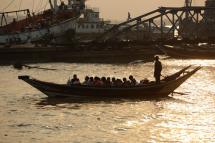 The sun sets as a small ferry boat loaded passengers leaves Wardan jetty to pass across Yangon river, in Yangon. Photo: Lynn Bo Bo/EPA