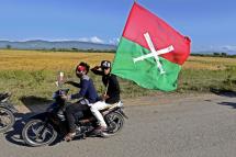 Kachin men saluting and holding the Kachin State flag as they follow a convoy of ethnic leaders in Myitkyina, Kachin State, Myanmar, 02 November 2013. Photo: Nyein Chan Naing/EPA
