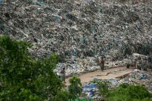 People walk past a garbage dump on the outskirts of Yangon on June 5, 2019. Photo: Sai Aung Main/AFP 