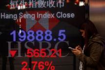 A person walks past a sign board displaying the closing numbers of the Hang Seng Index, which fell by 565.21 points, or 2.78 percent lower, to finish the day at 19,888.5, in Hong Kong, China, 11 January 2016. Photo: Alex Hofford/EPA

