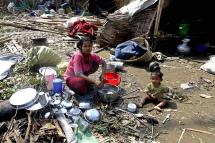 A Rohingya woman washes dishes near her damaged house at the Thae Chaung Muslim internally displaced people (IDPs) camp near Sittwe, Rakhine State, Myanmar, 17 May 2023. Photo: EPA