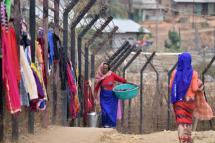 File Photo: An Indian woman carries her laundry past washing hanging up to dry on the India-Myanmar border fencing at Moreh on March 10, 2017. / Photo: AFP