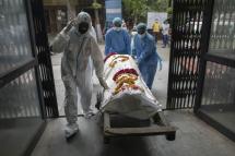 Orderlies (in blue) and a relative push a handcart carrying the body of a person who died from coronavirus to a furnace at the Nigambodh Ghat crematorium in New Delhi (Photo: AFP)