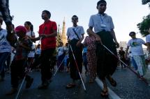 Visually impaired persons and helpers walk pass Sule pagoda as they take part in a rally to mark International White Cane Day, in Yangon, Myanmar, 15 October 2018. Photo: Lynn Bo Bo/EPA