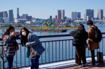 Visitors wearing masks take photos near the Olympic rings in Tokyo, Japan, 06 March 2020. Photo: EPA