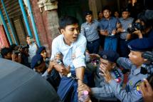 Police push detained Reuters journalist Kyaw Soe Oo (C) into a vehicle as detained Reuters journalist Wa Lone (C, back) is also escorted by police officers after their trial hearing in Yangon, Myanmar, 11 April 2018. Photo: Lynn Bo Bo/EPA-EFE
