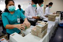 Staff members of the Asia Green Development Bank count Myanmar Kyat notes with machines at Sule branch office, in Yangon, Myanmar, 14 December 2016. Photo: EPA