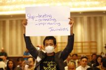 A masked protester holds up a sign in protest while Information Minister U Ye Htut is speaking during the opening session of the IPI World Congress on media freedom in Yangon on March 27, 2015. Photo: Hong Sar/Mizzima

