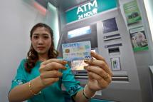 A staffer of the Asia Green Development Bank displays a debit card in front of ATM machine during the opening ceremony of the Myanmar Payment Union Data Center at the Central Bank of Myanmar, in Yangon, Myanmar, 14 September 2012. Photo: Lynn Bo Bo/EPA
