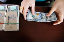 A money changer handles a transaction of US dollar and Myanmar Kyats. Photo: EPA