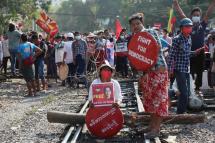 Demonstrators holding placards calling for the release of Aung San Suu Kyi block railway tracks during a protest in Mandalay, Myanmar, 17 February 2021. Photo: Kaung Zaw Hein/EPA