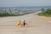 A man rides his bike across a road carrying toys to sell in Myanmar's city of Naypyidaw. Photo: EPA
