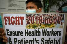A health worker wearing a face mask holds a placard during a protest in front of a government hospital in Manila (AFP/File / Ted ALJIBE)