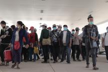 Myanmar nationals wearing facemasks amid concerns over the spread of the COVID-19 coronavirus walk at the immigration post in Myawaddy near the Thai border on March 23, 2020, as thousands of people crossed from Thailand as the border crossings were due to close because of the growing pandemic. Photo: AFP