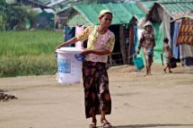 A woman carries a water bucket through the Dar Baing Muslim refugee camp near Sittwe, Rakhine State, western Myanmar, 10 November 2014. Photo: Nyunt Win/EPA
