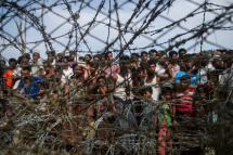 Rohingya refugees gather behind a barbed wire fence in a temporary settlement setup in a border zone between Myanmar and Bangladesh. Photo: AFP