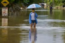 A woman walks along a road submerged by floodwaters following heavy monsoon rains in Mentakab town in Malaysia's Pahang state on January 8, 2021. Photo: AFP