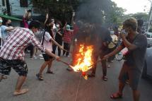 (File) Demonstrators flash the three-finger salute and burn the Myanmar National flag during an anti-military coup protest in Yangon, Myanmar, 24 November 2021. Photo: EPA