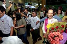 Myanmar opposition leader Aung San Suu Kyi (R) hands over flowers to her assistant as she arrives at Yangon International Airport ahead of her departure for China, in Yangon, Myanmar, 10 June 2015. Photo: Nyein Chan Naing/EPA
