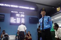 A security guard stands near a digital signboard displaying the currency exchange rates at Thain Phyu Money Changer Centre in Yangon. Photo: Mizzima
