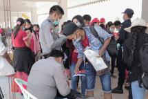 Myanmar nationals wearing facemasks amid concerns over the spread of the COVID-19 coronavirus speak with officials at the immigration post in Myawaddy near the Thai border on March 23, 2020, as thousands of people crossed from Thailand as the border crossings were due to close because of the growing pandemic. Photo: AFP