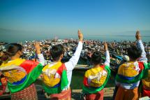 Members of the Shan ethnic minority wearing traditional Shan dress make the three-finger salute as others hold signs during a demonstration against the Myanmar military coup in Inle lake, Shan state on February 11, 2021. Photo: AFP