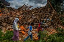 Children of earthquake victims walk past a collapsed house at Cugenang village in Cianjur, West Java on December 1, 2022, ten days after a 5.6-magnitude earthquake left 328 people dead. Photo: AFP