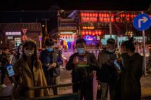 People wearing face masks as a preventive measure against the Covid-19 show a QR code "Health Kit" displayed on their smartphone before entering a crowded area on a street in Beijing on October 16, 2020. Photo: AFP