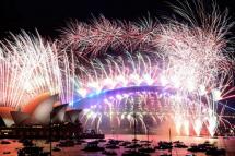 New Year’s Eve fireworks light up the sky over Sydney’s iconic Harbour Bridge and Opera House (L) during the fireworks show on January 1, 2022. DAVID GRAY / AFP